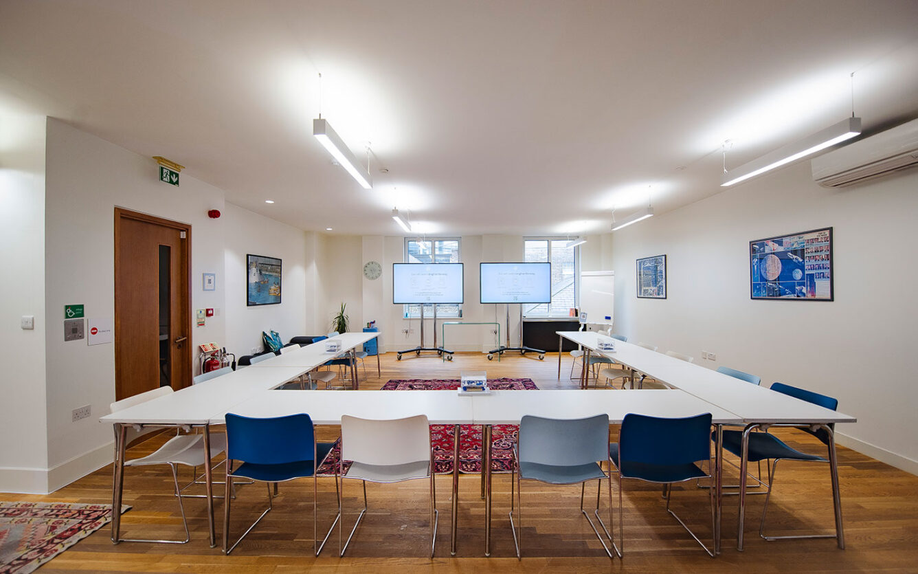 Large board room style meeting with bright lights in Liverpool Street with large monitors