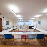 Large board room style meeting with bright lights in Liverpool Street with large monitors